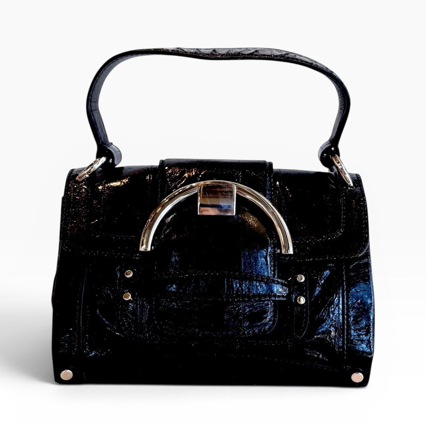 The Pearl black patent leather handbag with a structured top handle and silver-tone circular hardware clasp.